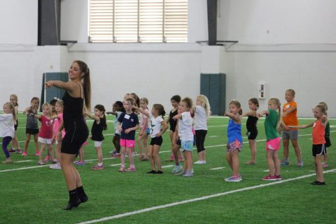 Sarah Scheffler (12) leads the junior Belles on the indoor field to practice for their performance at the game on Thursday. 